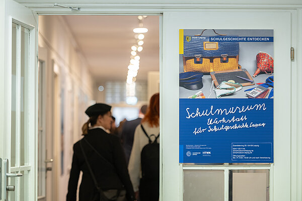 Das Leipziger Schulmuseum wird 25 Jahre alt. Frau geht durch Tür, daneben ein Plakat