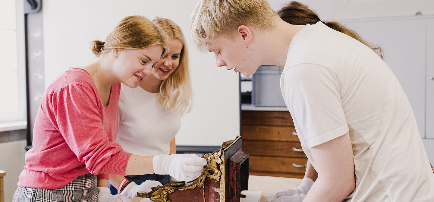 Studierende untersuchen ein historisches Objekt