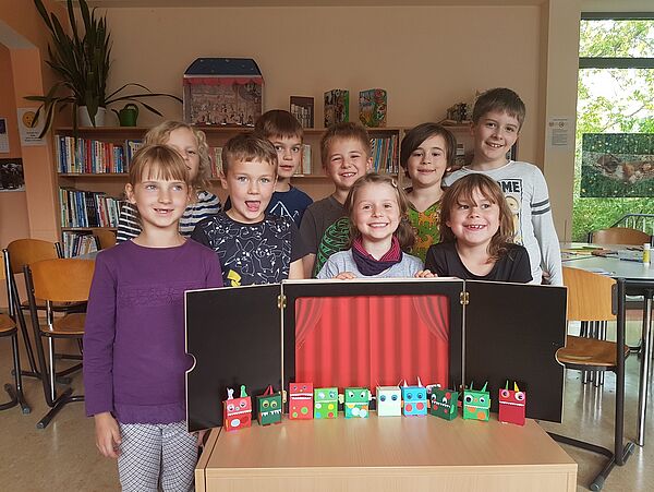 Kine Kindergruppe steht hinter dem Puppentheater