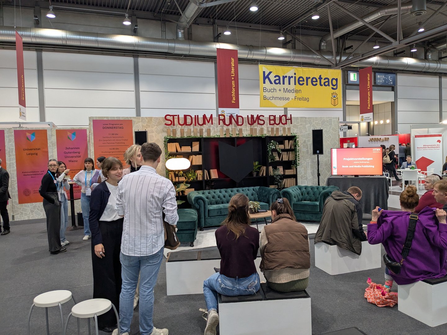 Lesesofa am HTWK-Buchmessestand Menschen an Messestand vor Sofa