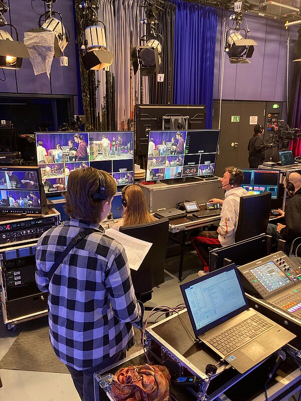 Personen in einem Regie-Raum mit vielen Bildschirmen