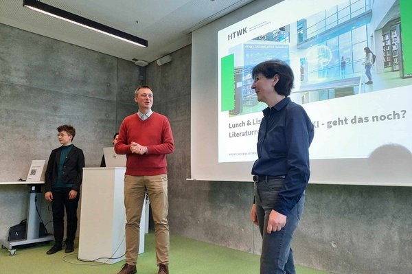 drei Personen vor einer Präsentation an einer Wand