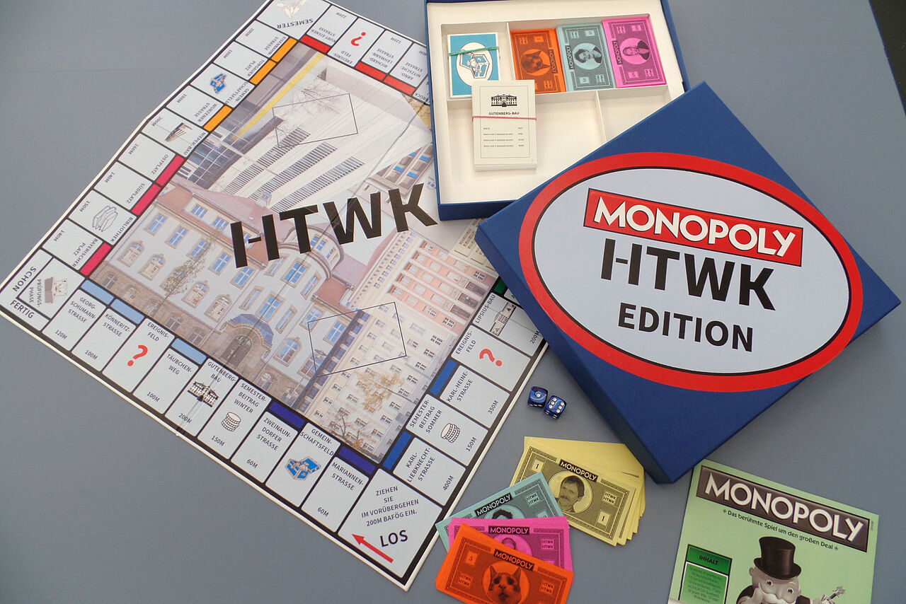 Eine Brettspiel, das an Monopoly angelegt ist. Der Titel ist Monopoly HTWK Edition. Links das Spielbrett, das mit Gebäuden der HTWK bedruckt ist. Rechts die quadratische Verpackung mit Aufschrift. Oben und unten die Spielgeldscheine in unterschiedlichen Farben.