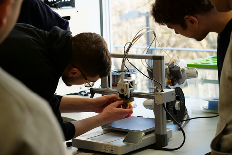 Studierender justiert Druckkopf an 3D-Drucker, Nahaufnahme