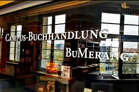 Blick durch die Scheibe in den Buchladen, Schriftzug "Campus-Buchhandlung BuMerang"