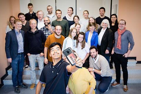 „Flucht als Krise“ in den Medien Gruppe verschiedener Menschen im Hintergrund und zwei Menschen mit Smartphone im Vordergrund