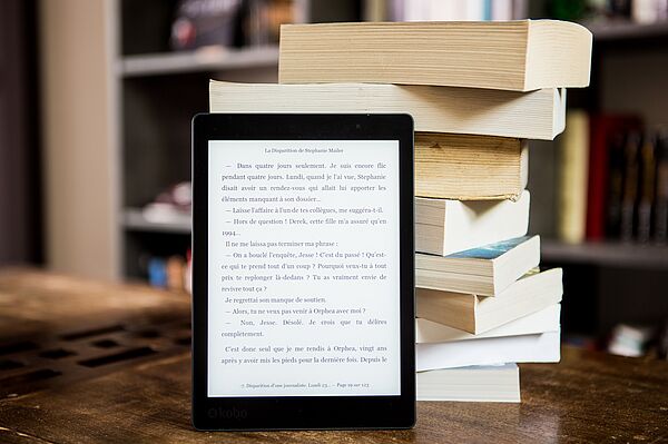 ein eBook Reader steht vor einem Buchstapel