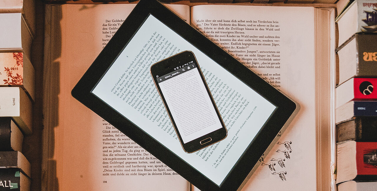 Smartphone und Tablet liegen auf einem Stapel Bücher