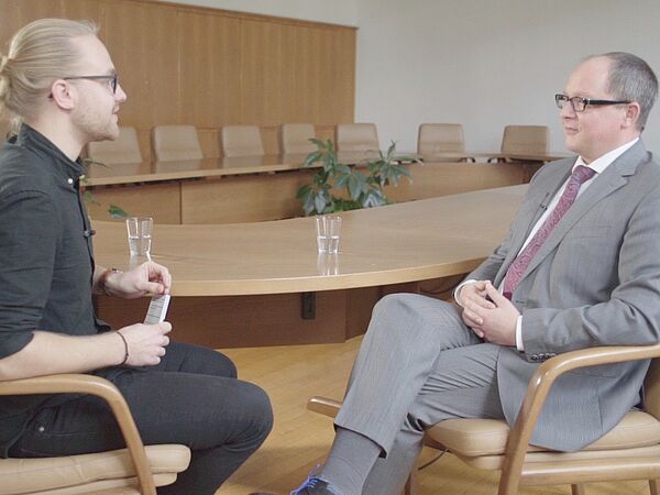 zwei Männer sitzen sich gegenüber und unterhalten sich