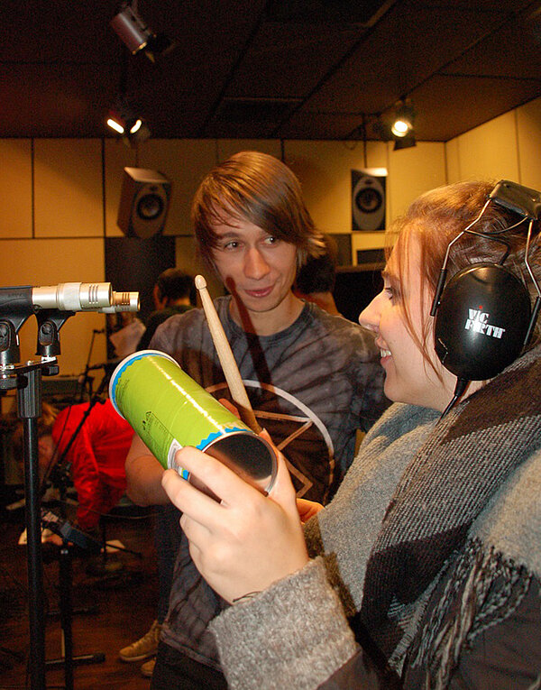 Studierende stehen im Studio und produzieren Musik mittels Alltagsgegenständen