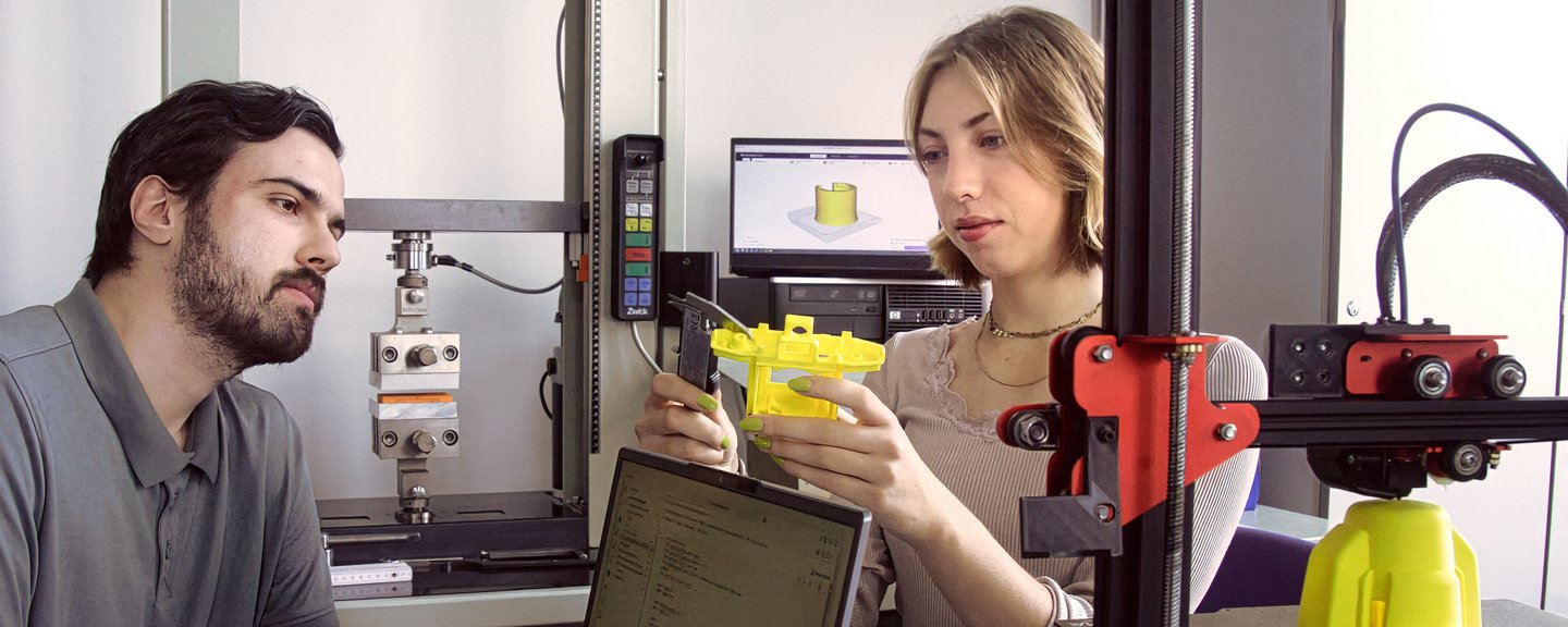 Zwei Studierende betrachten ein 3D-gedrucktes Objekt