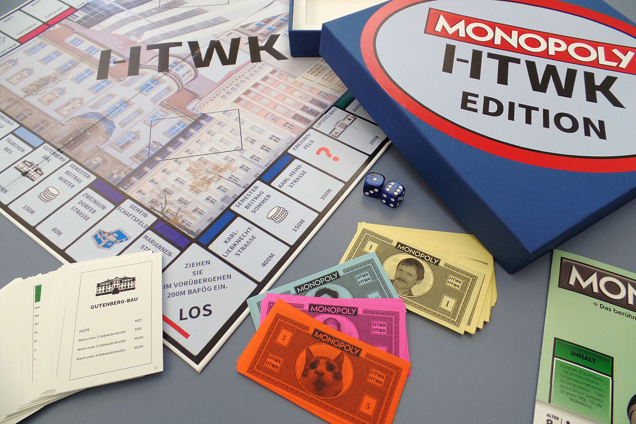 Eine Brettspiel, das an Monopoly angelegt ist. Der Titel ist Monopoly HTWK Edition. Links das Spielbrett, das mit Gebäuden der HTWK und dem Schriftzug HTWK bedruckt ist. Rechts die quadratische Verpackung mit Aufschrift. Unten Ereigniskarten und die Spielgeldscheine in unterschiedlichen Farben.