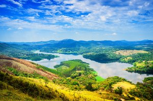 Grüne, bergige Landschaft mit einem See und blauem Himmel