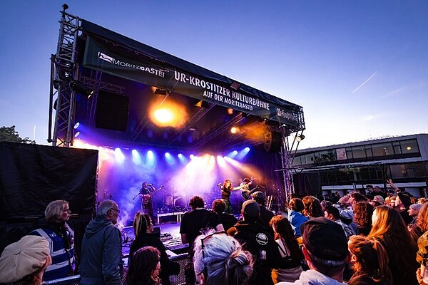 Ein Blick aus der Besuchermenge auf die Bühne des Festivals bei Sonnenuntergang.
