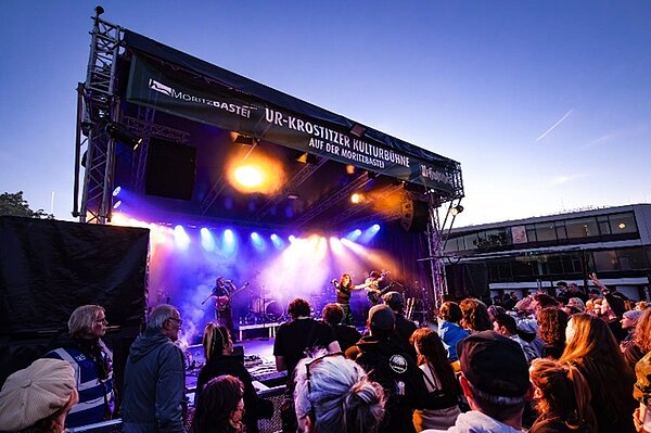 Ein Blick aus der Besuchermenge auf die Bühne des Festivals bei Sonnenuntergang.