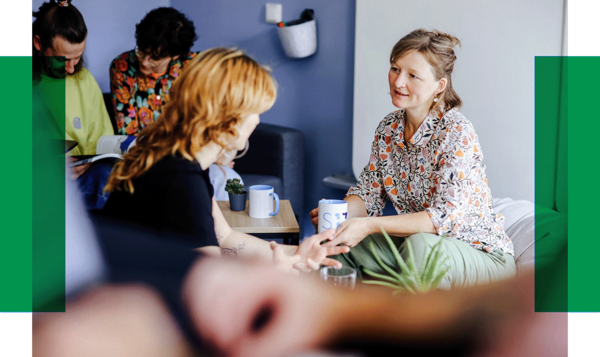 Gespräch in gemütlicher Runde Fünf Personen sitzen in einem hellen Raum, unterhalten sich und trinken Kaffee. Zwei Frauen sprechen sich direkt gegenüber.. Zur Seite Unterstützung auf Augenhöhe mit Ment4Science.