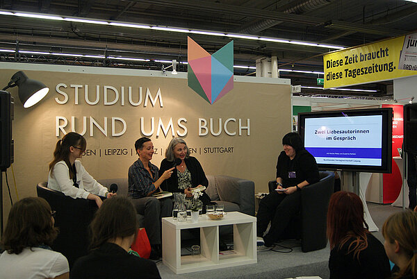 Auf einem Sofa sitzende Studierende sind im Gespräch mit den Autorinnen Monika Peetz und Susanne Rehlein