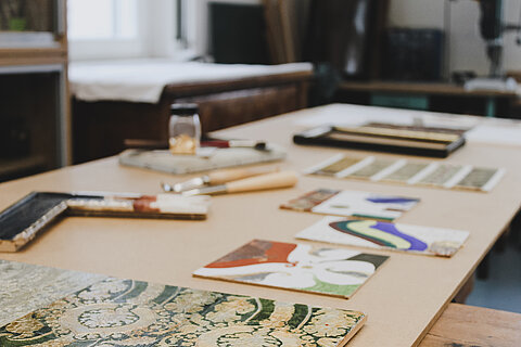 Arbeiten im Labor für Werkstoffkunde Verschiedene Werkstoffe der Museologie, wie Bilderrahmen oder Stoffe, auf einem Tisch