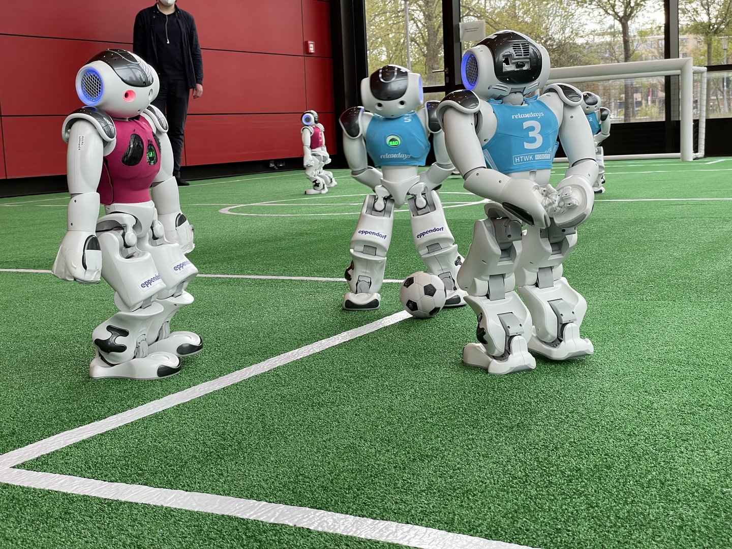 Humanoide Fußballroboter der HTWK Robots auf einem Spielfeld.
