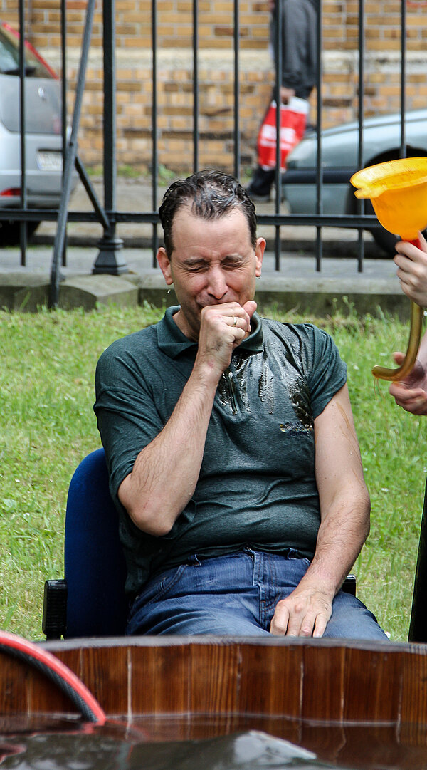 Professor Hartmann sitzt mit völlig durchnässter Kleidung auf einem Stuhl