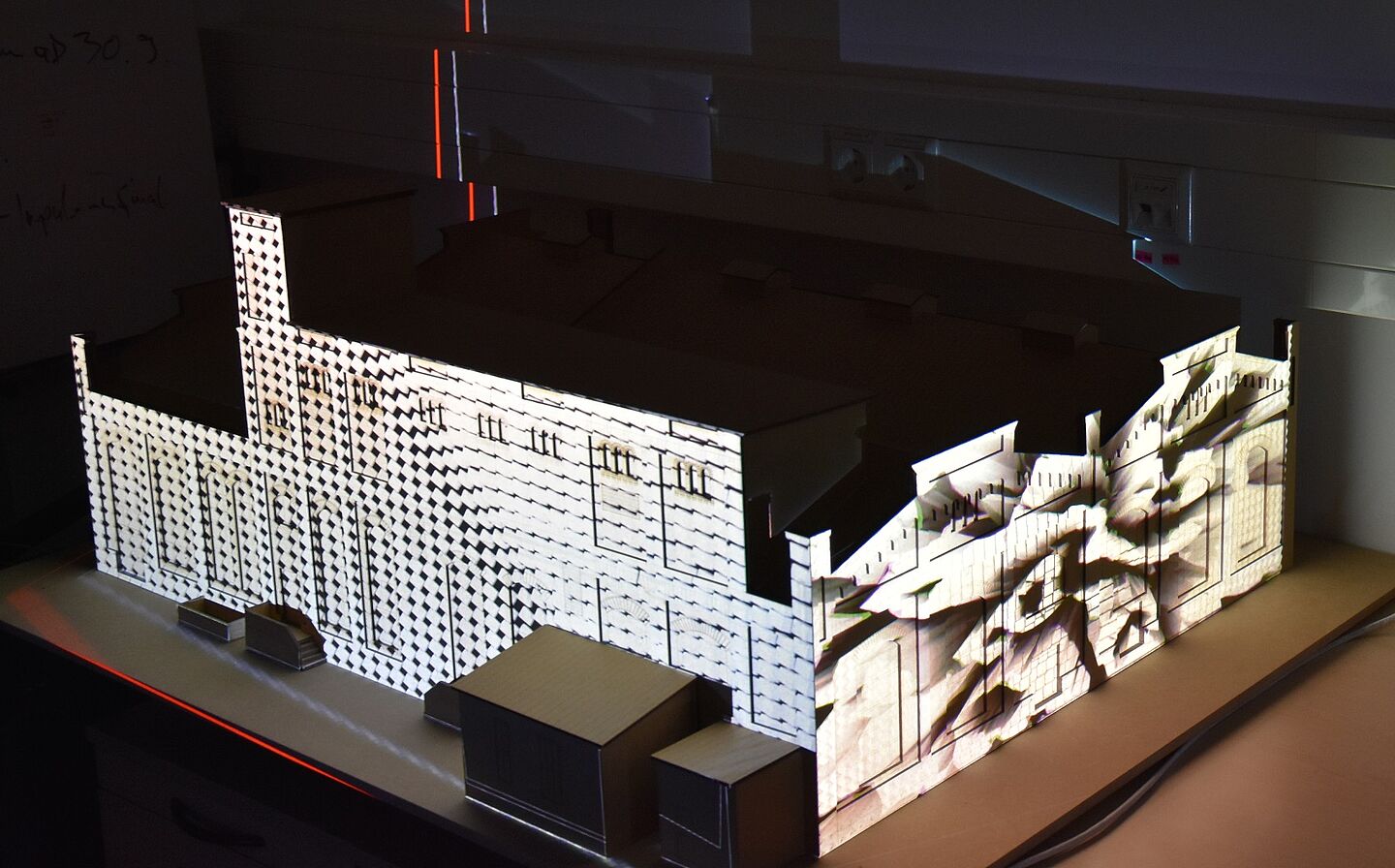 Modell eines großen Hauses, darauf ist eine Lichtprojektion zu sehen
