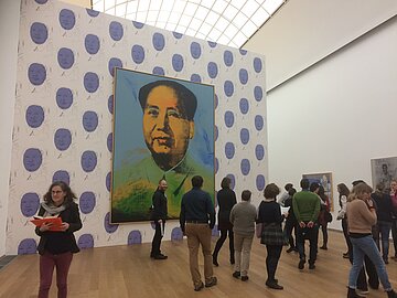 Kooperationspartner_innen Blick in einen großen Ausstellungsraum, in dem ein Bild von Mao Tse Tung ausgestellt ist.
