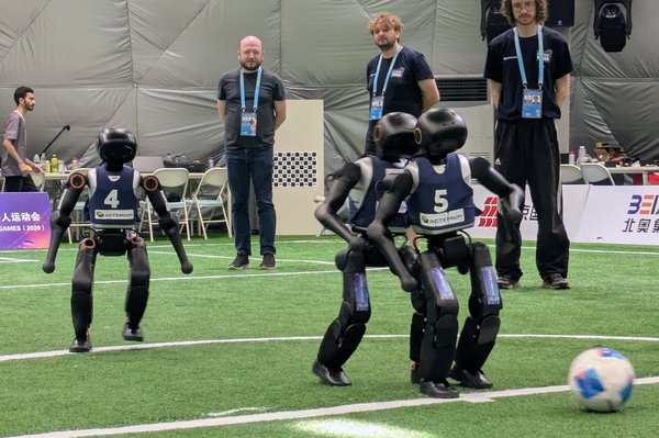 Humanoide Roboter spielen Fußball und Menschen schauen zu