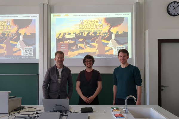 Professor Kulisch, Dr. Nestler und Dr. Graebling stehen im Hörsaal und im Hintergrund ist die Präsentation zu sehen.