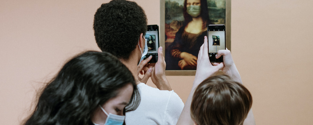Drei Jugendliche mit Atemschutzmaske fotografieren die Mona Lisa mit ihrem Smartphone