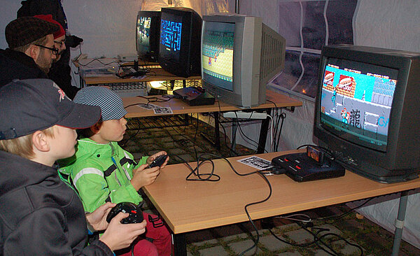 Kinder spielen an einem dafür bereitgestellten Fernseher ein Konsolenspiel