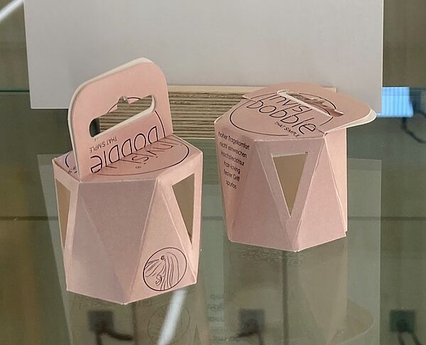 Sechseckige Pappschachteln in Rosa, raffiniert gefaltet, mit Henkel.