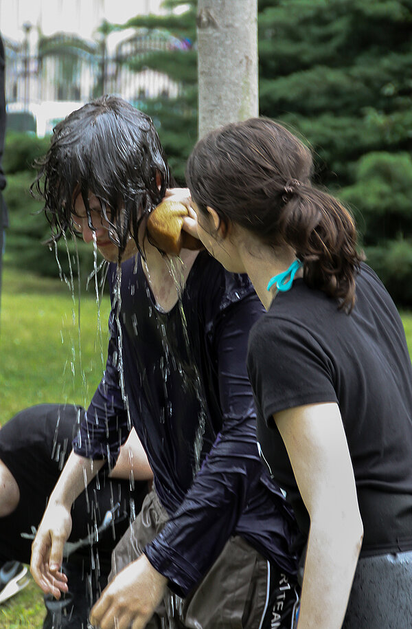 Zwei Studenten waschen sich mit kaltem Wasser und in voller Kleidung