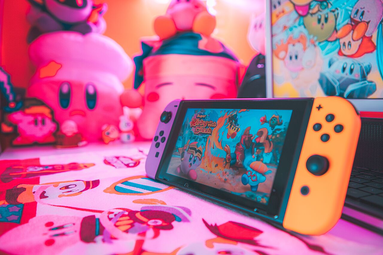 Nintendo Switch Controller auf einem Tisch mit Plüschtieren und pinker Beleuchtung im Hintergrund