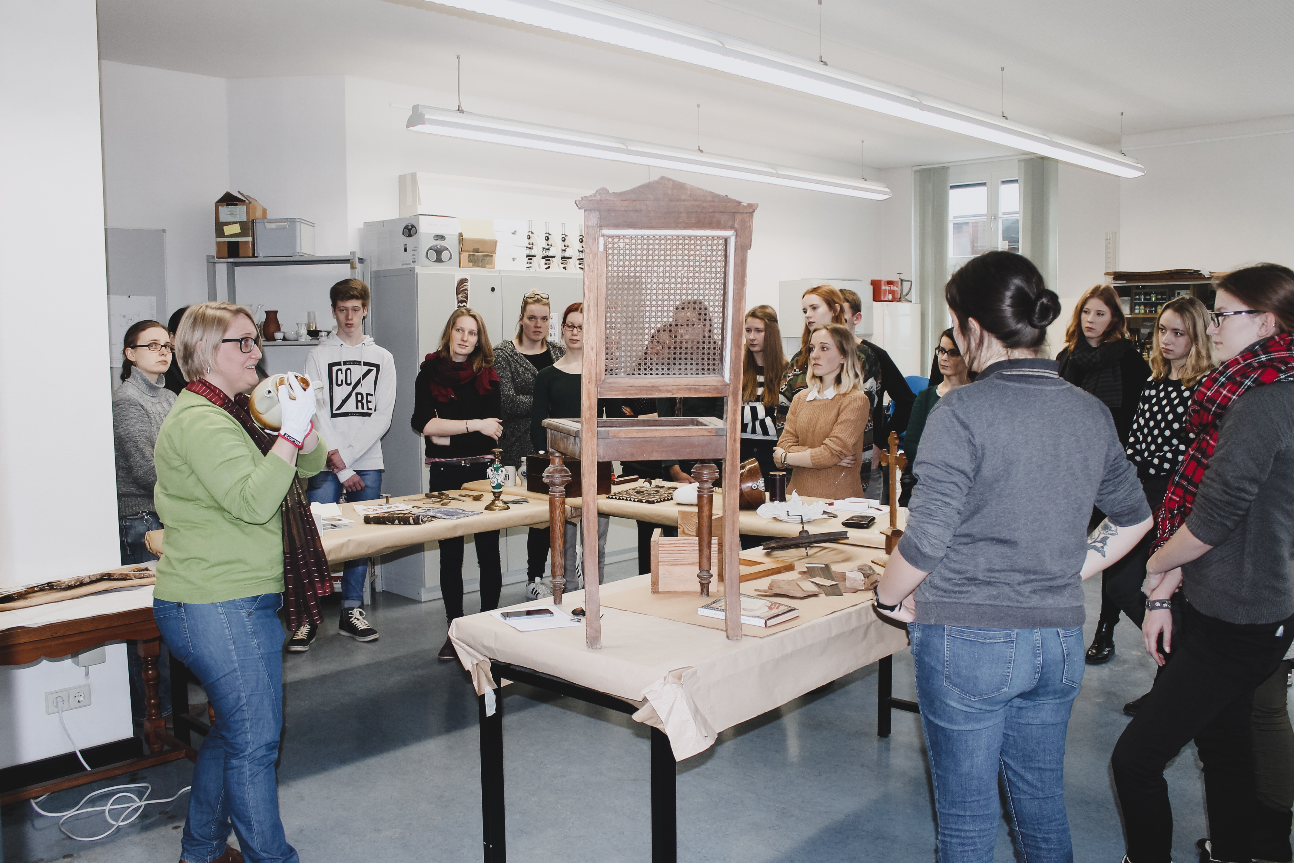 Arbeiten im Labor der Bestandsdokumentation Verschiedene Objekte auf Tischen werden Studierenden gezeigt