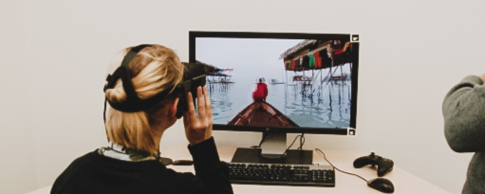Eine junge Besucherin hat eine Virtual Reality Brille auf und schaut sich ein passendes Video an.