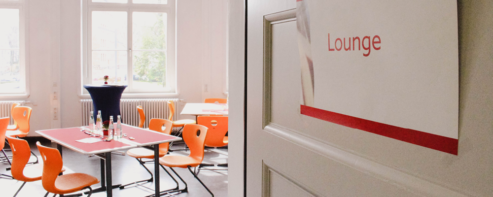 Blick in die Lounge-Räume des publishing and printing forums mit orangefarbenen Stühlen.