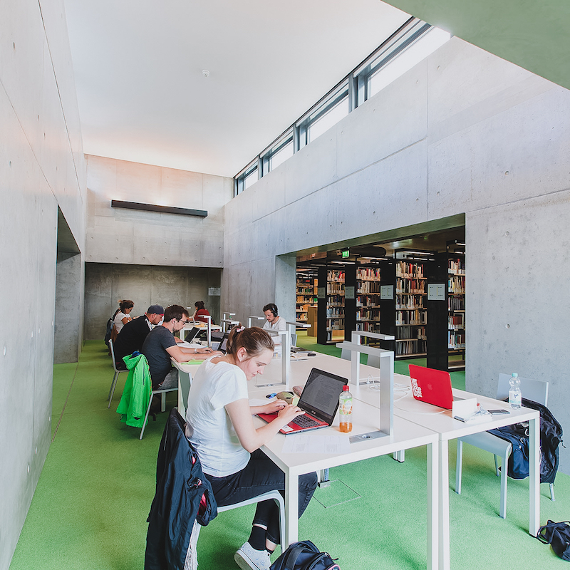 Bild zeigt einen Raum mit Schreibtischen und Studenten die an ihren Laptops arbeiten.