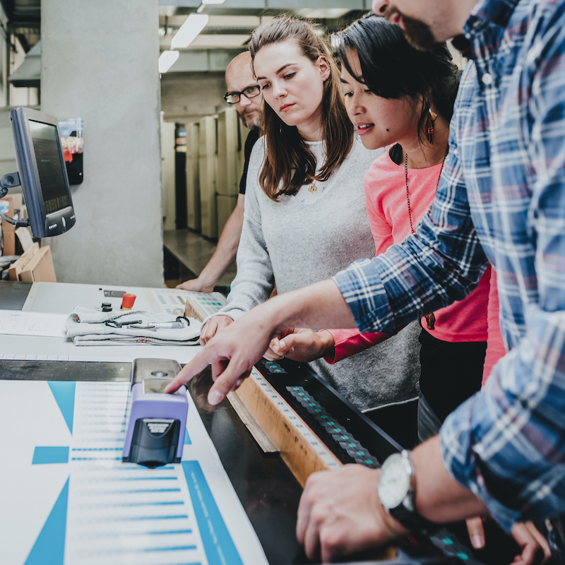 Bild zeigt 4 Personen die an einer Maschine etwas abmessen.