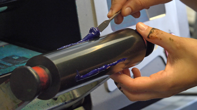 Makroaufnahme im Labor. Ein Kunststoff wird per Hand auf eine Walze aufgetragen.
